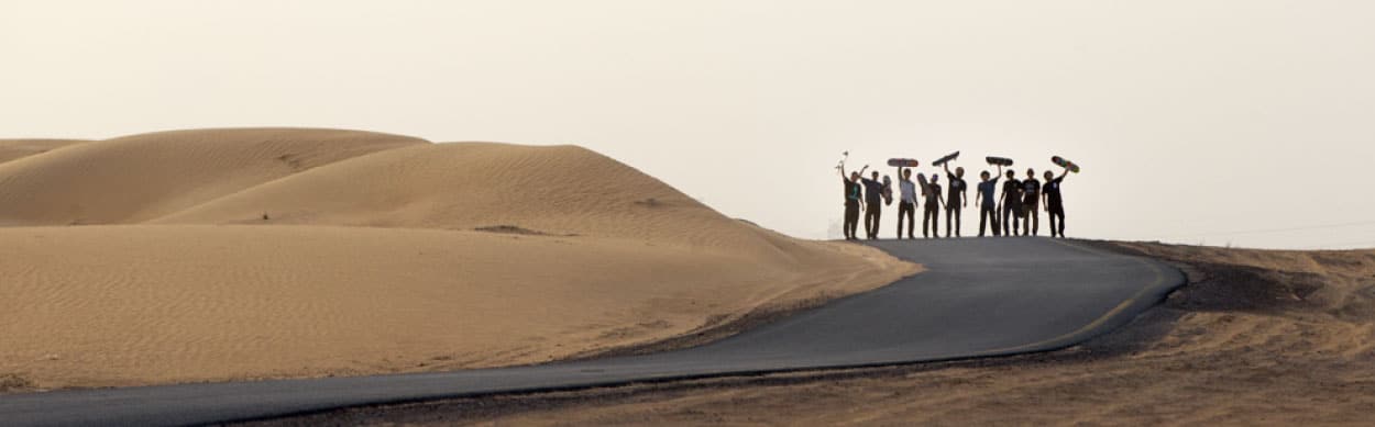 sand dunes and people holding skateboards in the air