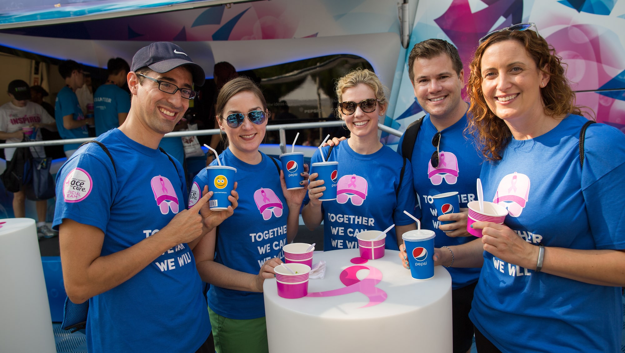 people smiling, holding pepsi cups, wearing the same blue tshirt